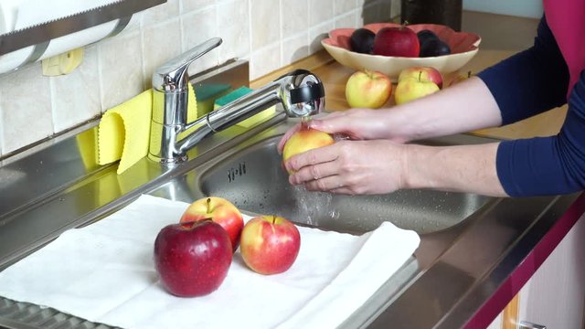 Woman hands washing fresh apple in kitchen under water stream. Wash fruits before eating. Protect health 4K ProRes HQ codec