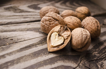 Walnuts on a grey textured wooden table. Assortment of nuts isolated on rustic old wooden background and splintered walnut with heart-shaped core. Walnuts close up