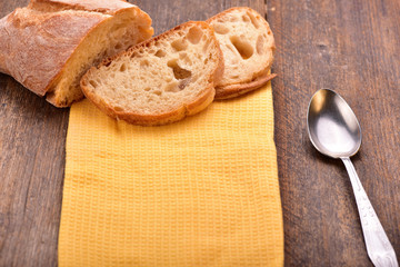 Homemade sliced bread with yellow napkin and spoon on wooden table.