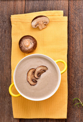 Mushroom cream soup on yellow napkin. Wooden table. Top view.