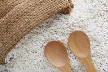 Wooden spoon of empty and hemp sack on organic white rice, gluti