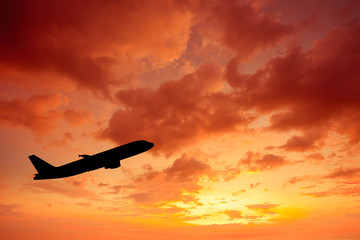 Naklejka na ściany i meble Silhouette of an airplane at sunset.