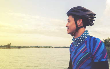 Young man with bicycle standing on the nearby lake in holiday mo