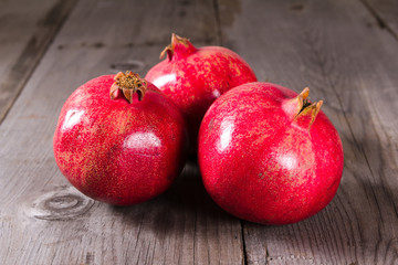 Some whole red pomegranate on rustic wooden unpainted table