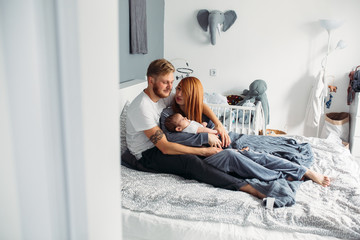 Happy family with newborn baby on the bed