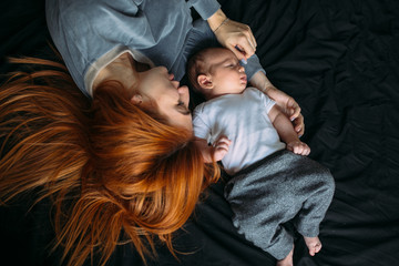 Happy mother with baby lying together on bed