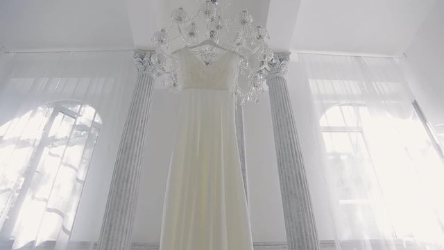 Wedding white dress hanging on chandelier inside space room