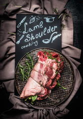 Lettering lamb shoulder cooking on black chalkboard with raw  lamb shoulder roast with string , ...