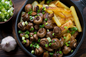 Closeup of a skillet with fried champignons and potato, top view