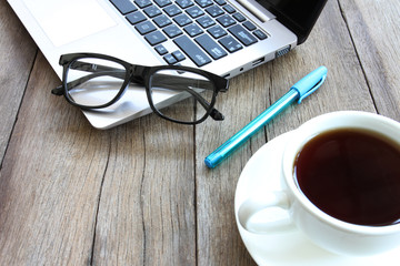 Eyeglasses and blue pen on the wooden work table.