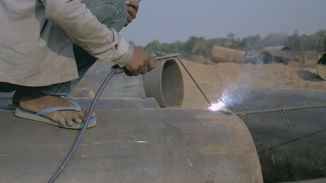 Close up of a welder worker welding on a steel pipe