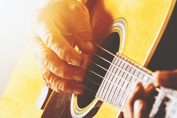 The old man's hand playing acoustic guitar