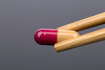 Orange pill in chopsticks on the black background