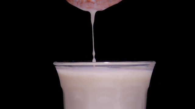 Dunking chocolate chip cookie in glass of milk, slow motion flm clip. Close up with black background.