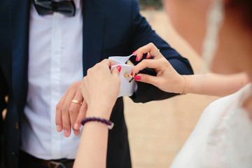 Fototapeta na wymiar Preparations for the wedding, the bride helps the groom to wear cufflinks