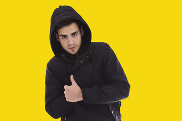 Young man with coat over yellow background