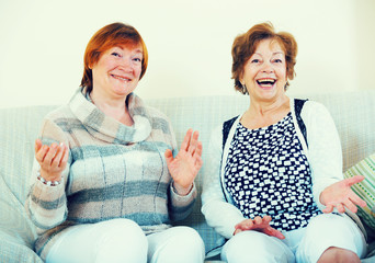 Female pensioners discussing something and laughing indoors