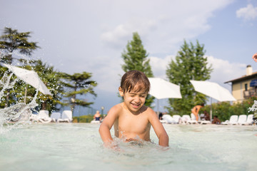 Young boy kid child splashing in swimming pool having fun leisur