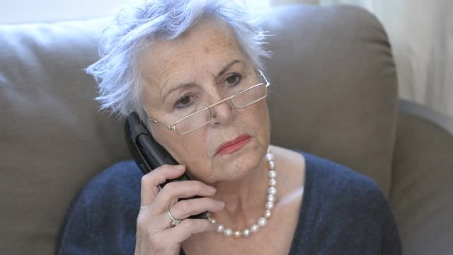 Attractive grey haired senior woman ringing a wrong number on the telefon 