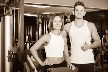 slim young man and woman taking pause between exercising in gym