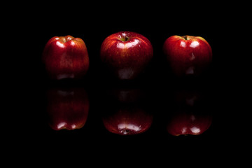 Three red apples isolated on black background