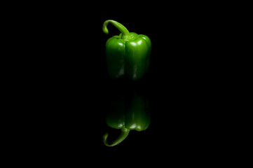 Whole green bell pepper isolated on black background