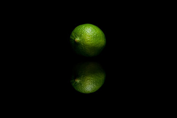 One whole green lime isolated on black background