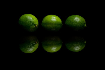 Three green limes isolated on black background
