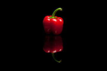 Whole red bell pepper isolated on black background