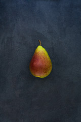 Whole red yellow pear isolated on gray slate stone background