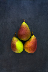 Three whole red yellow pears isolated on gray slate stone backgr