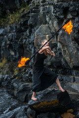 Girl in a black suit with flaming torches .