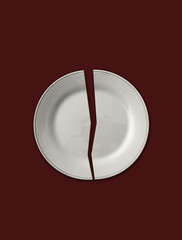 Isolated broken white plate in half on solid brown background