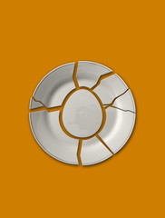 Isolated broken plate in the shape of an egg on solid yellow bac