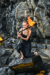 Girl in a black suit with flaming torches .