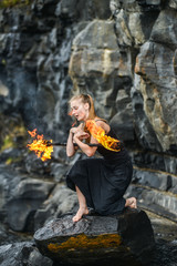 Girl in a black suit with flaming torches .