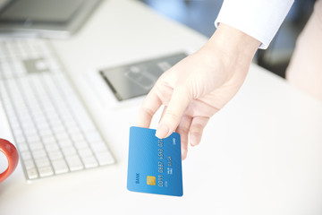 Online banking. Close-up shot of a young businesswoman sitting in the office in front of computer and holding credit card while typing data. 