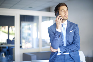 Professional man with handy. Shot of a young businessman making call while standing in the office.