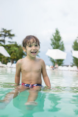 Young boy kid child splashing in swimming pool having fun leisur