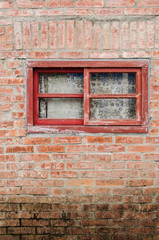 Fototapeta na wymiar Old window with red wooden frames on brick wall. Curtain drawn down inside the window.
