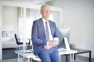 Senior professional man portrait. Shot of a thoughtful senior businessman standing at office while on coffee break.