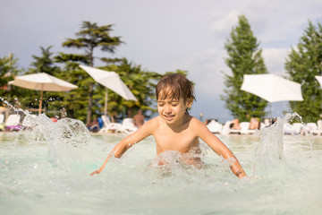 Young boy kid child splashing in swimming pool having fun leisur