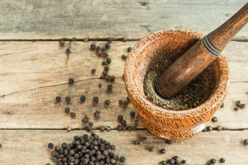 black pepper on wooden table texture with grounded black pepper in wooden mortar with wooden...