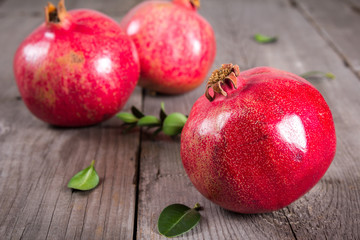 Some whole red pomegranate on rustic wooden unpainted table