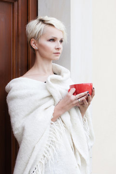 beautiful woman wrapped in a blanket with a cup in his hands
