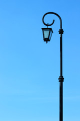 Fototapeta na wymiar Tall black street lamp on background blue sky