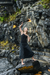 Girl in a black suit with flaming torches .