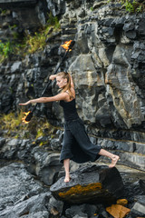 Girl in a black suit with flaming torches .