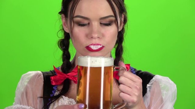 Oktoberfest girl flirting and drinking beer from a glass. Green screen. Slow motion
