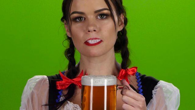 Oktoberfest girl flirting and drinking beer from a glass. Green screen